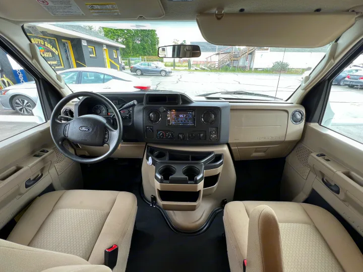 RV rental Ford E-Series driver's cockpit with dashboard, steering wheel, radio, and beige front seats.. THOR MOTOR COACH Freedom Elite 2019
