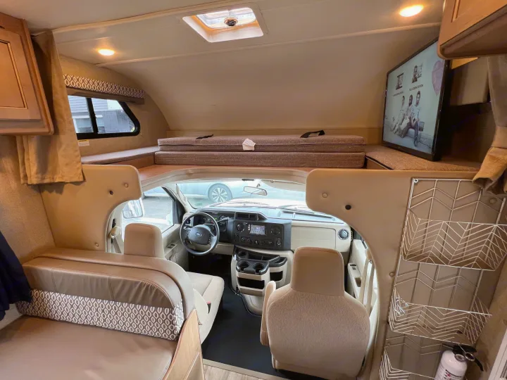 RV rental interior: cozy living space with bed over cab, cockpit, and TV. Ready for adventure!. THOR MOTOR COACH Freedom Elite 2019