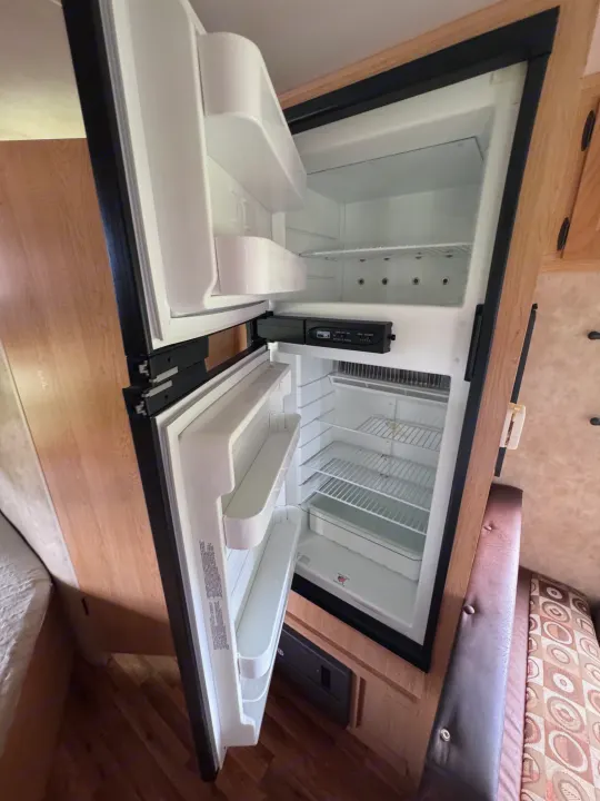 Clean, empty RV rental refrigerator with shelves and freezer doors open, ready for your trip.. kz Coyote 2010