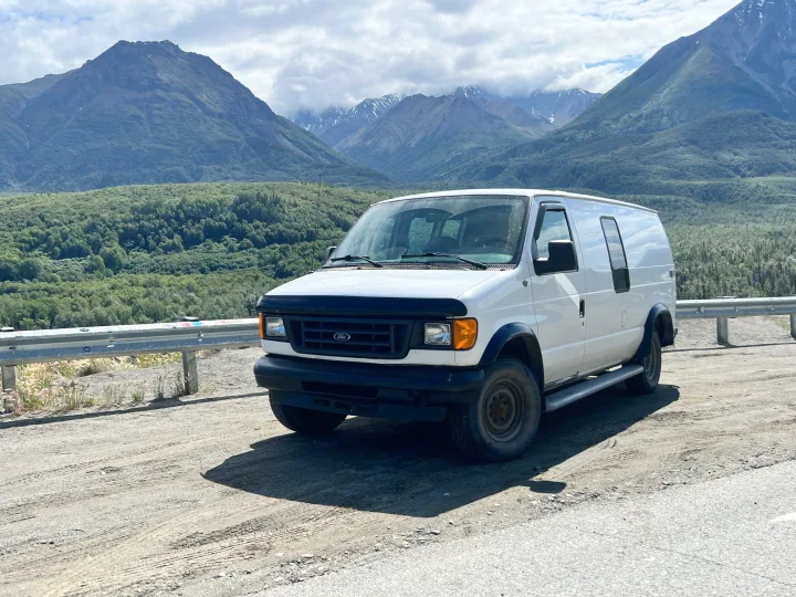 White Ford van in a mountain landscape, perfect for adventure. Similar to an RV rental setup.. Ford Econolline 250s 2006