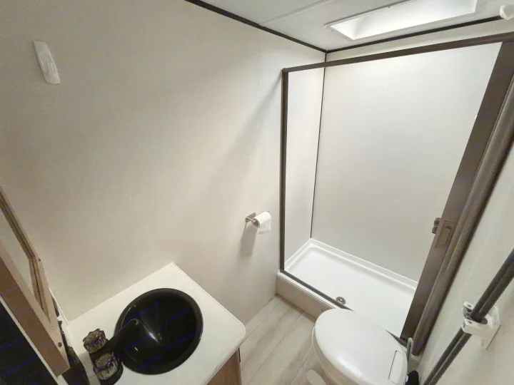 Explore this functional RV rental bathroom. Features a compact shower, toilet, and vanity sink, ready for travel adventures.. Keystone Coleman Light 2026