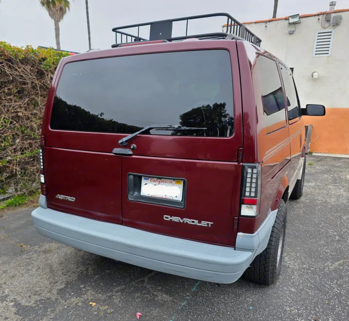 Rear of a maroon Chevrolet Astro van with roof rack & LED taillights. Could be an RV rental for road trips.. Chevrolet Astro 2003