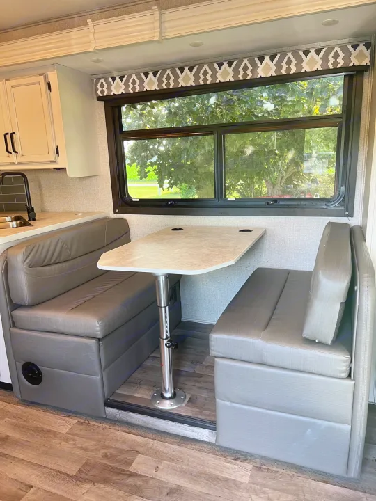 RV rental: Spacious dinette with gray seating, table, and kitchen in a well-lit interior.. Jayco Redhawk 2021