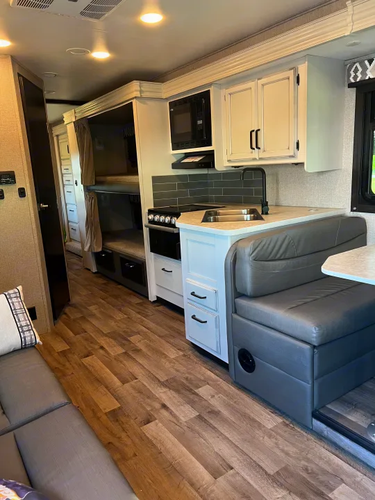 Spacious RV rental interior featuring a modern kitchen, comfortable dinette, and cozy bunk beds. Perfect for travel.. Jayco Redhawk 2021