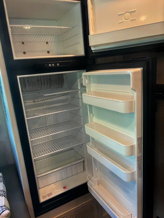 Inside an RV rental, a clean, empty refrigerator with a separate freezer compartment, ready for supplies.. Jayco Redhawk 2021