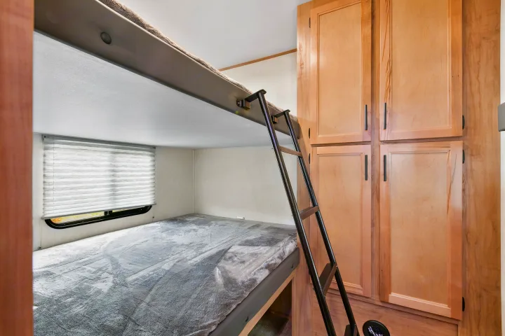 RV rental: bunk bed sleeping area with a ladder, window with blinds, and wood storage cabinets.. Cherokee limited Arctic Wolf 2023
