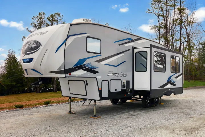 Modern Cherokee Arctic Wolf fifth-wheel RV rental, parked on gravel, ready for camping travel adventures.. Cherokee limited Arctic Wolf 2023