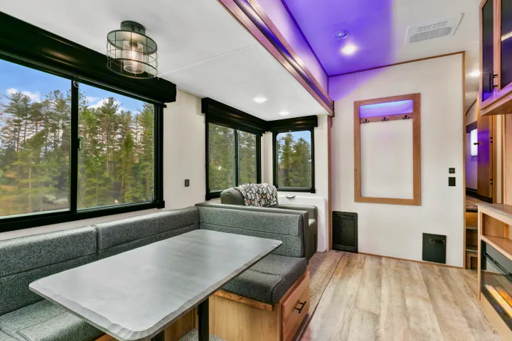 Bright RV rental living space with a comfortable dinette, scenic forest views, and stylish purple ambient lighting.. Cherokee limited Arctic Wolf 2023