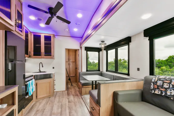 Modern RV rental interior showcasing a full kitchen, a cozy dinette, and a living area, all illuminated by purple ambient lighting.. Cherokee limited Arctic Wolf 2023