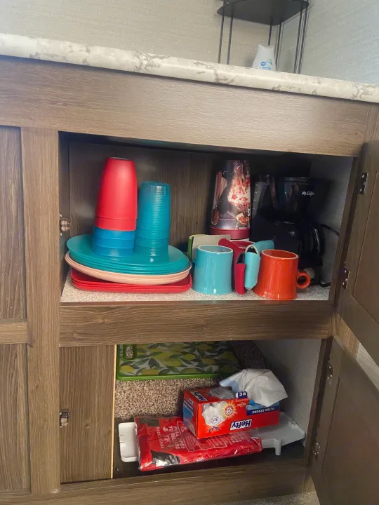 RV rental kitchen cabinet showing organized dishes, a Mr. Coffee maker, and various supplies.. Keystone RV Bullet Crossfire 2018