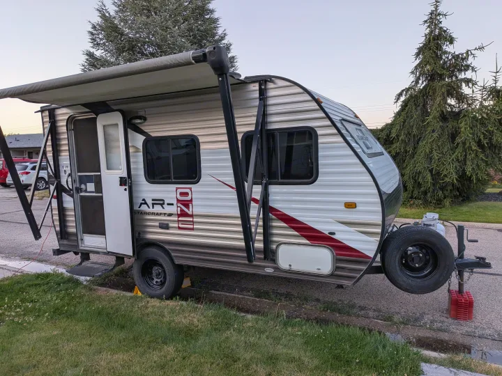 A Starcraft AR-ONE travel trailer, with its awning out & door open, is parked on a street. Perfect for your next RV rental.. Starcraft AR-One 2015