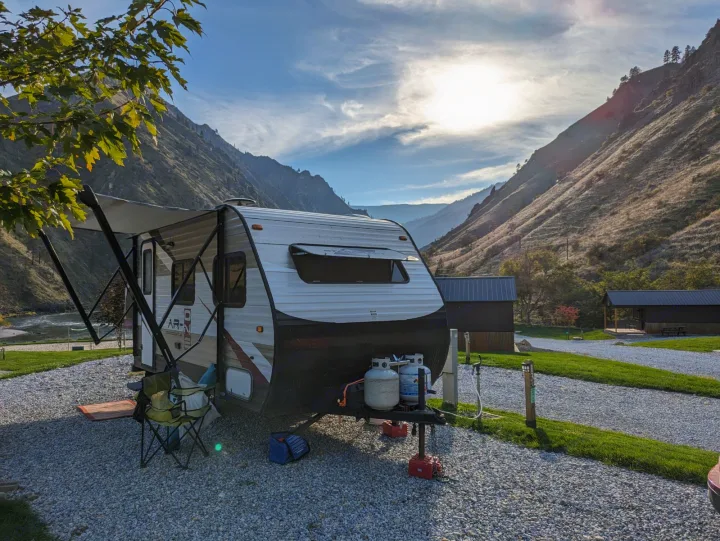A modern rv rental travel trailer at a scenic riverside campsite, surrounded by towering mountains.. Starcraft AR-One 2015