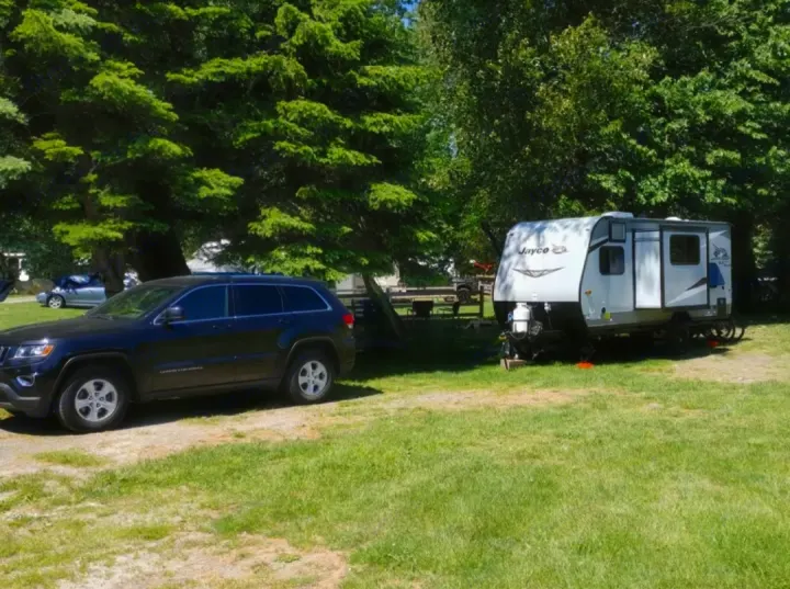 Enjoy your next rv rental adventure! This Jayco travel trailer and SUV are ready for camping at a sunny campground surrounded by trees.. Jayco Jay Flight 2021