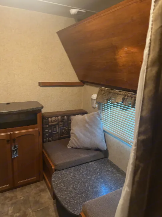 This RV rental interior features a cozy dinette with dark grey seating, a speckled table, and a wood-toned cabinet.. Heartland Trail Runner 2013
