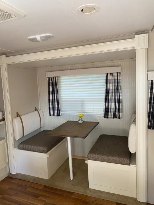 Inside an RV rental, a stylish dinette with upholstered booth seating, a table, and plaid curtains.. Cruiser RV Fun Finder X 2011