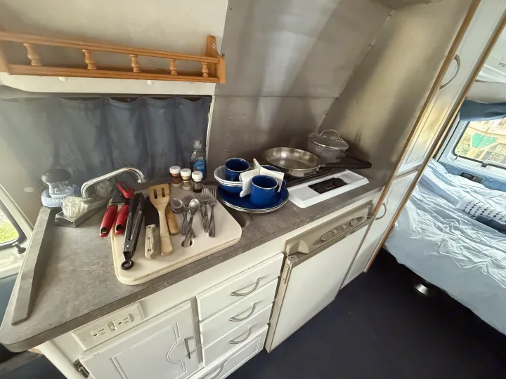 RV rental: functional kitchen setup with sink, utensils, cookware, compact fridge, and adjacent bed area.. Pleasure Way Excel 2001