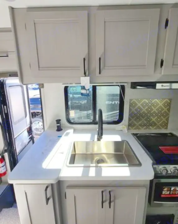 RV rental kitchen: light gray cabinets, white counters, stainless steel sink, and stove. A modern, functional space ready for adventure.. Forest River Coachmen Freelander 2025