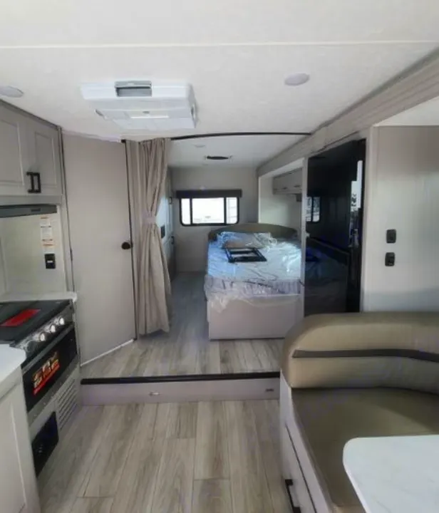 Spacious RV rental interior featuring a modern kitchen, cozy bedroom, and comfortable dinette area with light wood floors.. Forest River Coachmen Freelander 2025