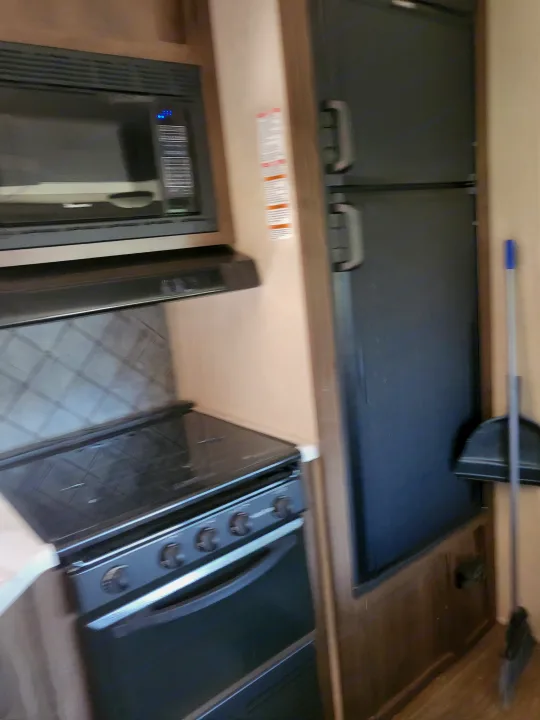RV rental kitchen featuring a modern microwave, electric stovetop, oven, and refrigerator. Essential appliances for any trip.. Forest River Palomino Puma 2018