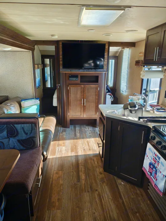 Inside an RV rental: a modern living space featuring a flat-screen TV, comfy dinette, and functional kitchen with Keurig.. Forest River Cherokee Grey Wolf 2016