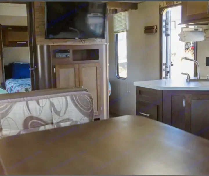 RV rental interior, showing the kitchen counter, entertainment area with TV, and a glimpse of the bedroom.. Forest River Cherokee Grey Wolf 2016