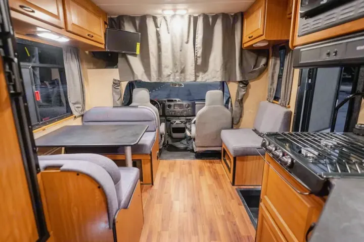 This RV rental's interior features a dining booth, full kitchen, and front cabin. Clean, modern, and ready for travel.. Thor Majestic 2017