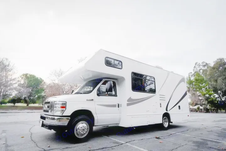 A bright white Class C rv rental with gray decals, parked in a lot surrounded by trees, ready for adventure.. Thor Majestic 2017