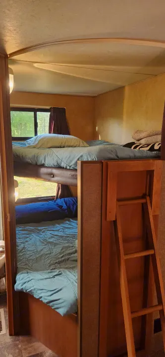 RV rental interior showing cozy bunk beds with light blue bedding and a wooden ladder. Ideal for family camping adventures.. Starcraft Autumn Ridge 2014