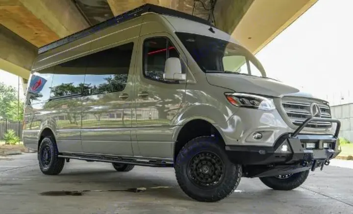 A light grey, lifted Mercedes-Benz Sprinter camper van with off-road tires and a custom bumper. Ideal for RV rental adventures.. Mercedes Benz Sprinter 2500 2024