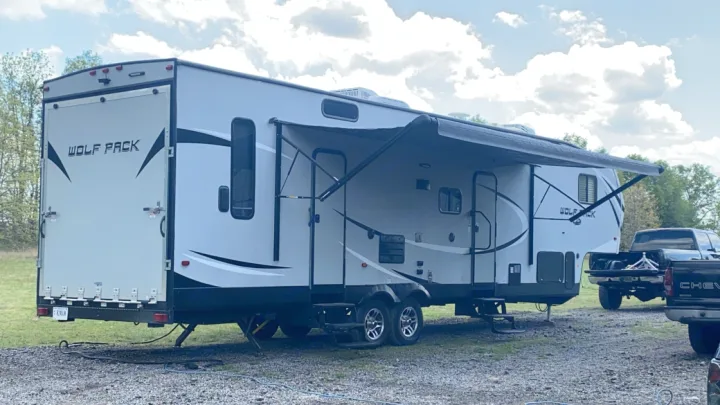 Grey Wolf Pack toy hauler RV rental parked on gravel with awning out. Perfect for your next outdoor adventure.. Forest River Wolf Pack 2018