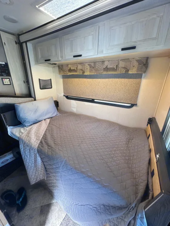Cozy RV rental interior with a comfortable single bed, overhead cabinets, and window, ready for your adventure.. Forest River Sunseeker Classic 2021