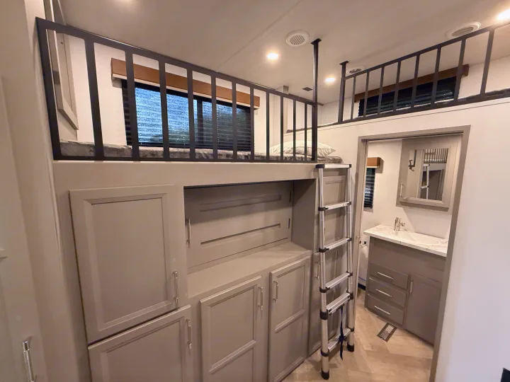 Modern RV rental interior: stacked bunk beds, ladder access, integrated storage, and a convenient compact bathroom.. Keystone Sprinter Wide Body 2025