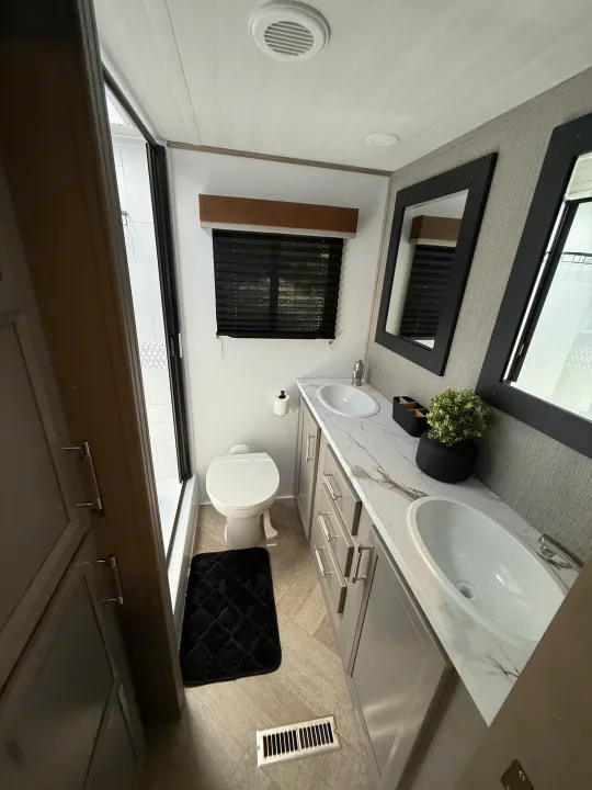 Modern RV rental bathroom with dual sinks, toilet, shower, and storage. Ideal for clean and comfortable journeys.. Keystone Sprinter Wide Body 2025