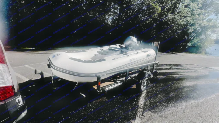 White inflatable boat with Honda motor on a Karavan trailer at the boat ramp, ready for lake fun. Perfect for RV rental adventures!. Ford Bronco Badlands 2023