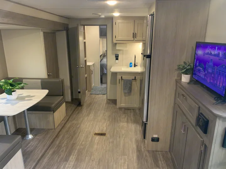 Spacious RV rental interior with modern kitchenette, dining booth, and bedroom. Ideal for adventures.. Forest River Aurora Aurora Light 2024