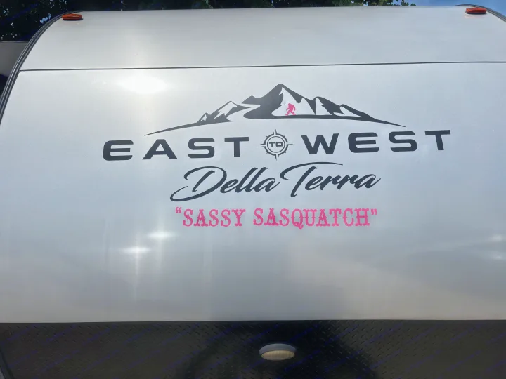 Front view of a silver East to West Della Terra travel trailer, branded 'Sassy Sasquatch' with a pink Bigfoot, ideal RV rental.. East to West Della Terra 2021
