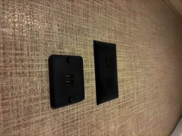 Black USB charging ports & AC outlets on a textured wall in an RV rental, providing power for your devices.. East to West Della Terra 2021