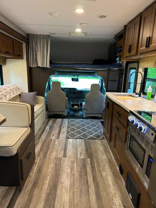 Inside an RV rental: a compact living space featuring a cozy dinette, well-equipped kitchen, and an overhead bed.. Forest River Sunseeker LE 2021