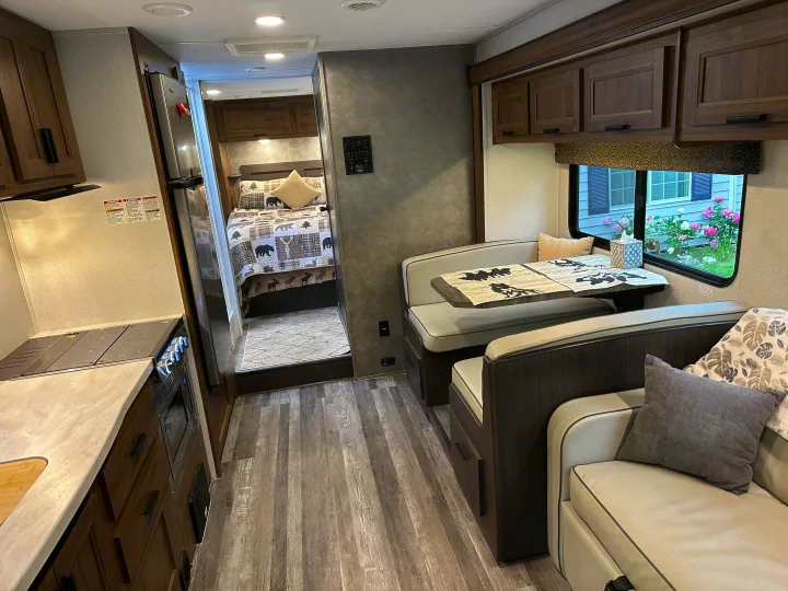 Spacious RV rental interior featuring a full kitchen, comfortable dining booth, and private bedroom, perfect for travel.. Forest River Sunseeker LE 2021