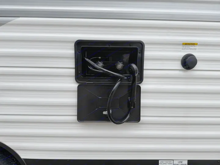 RV rental side with an open outdoor shower, revealing hose, controls, caution notice. Labels detail grey water tank and low point drain.. Jayco Jay Flight 2025