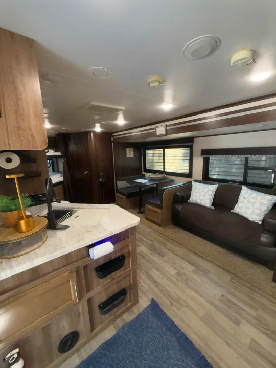 Spacious RV rental interior featuring a kitchen, dinette, sofa, and bunk beds, showcasing a comfortable living space.. Jayco Jay Feather 2019