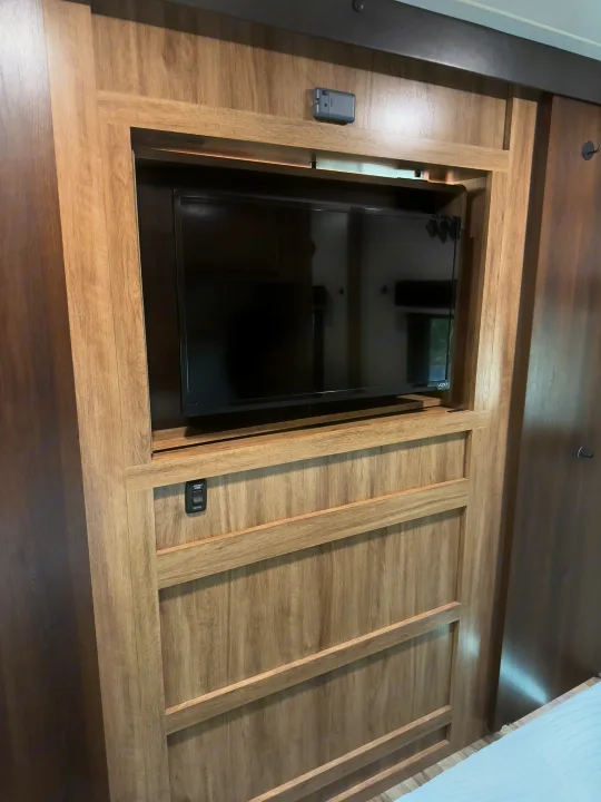 RV rental bedroom with built-in TV, climate control, speaker switch, and wood cabinetry.. Jayco Jay Feather 2019