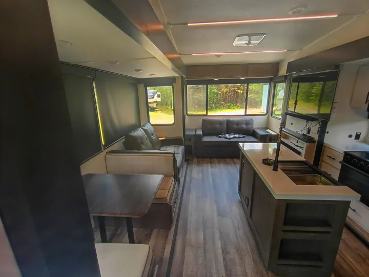 Modern RV rental interior: a comfy living area, dining booth, and full kitchen, perfect for road trips.. Forest River Arctic Wolf 2025