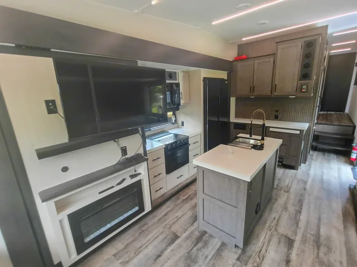 Spacious RV rental interior featuring a full kitchen with an island, modern appliances, and a living area with a fireplace.. Forest River Arctic Wolf 2025