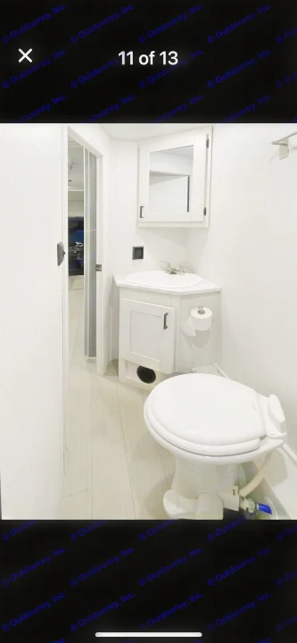 Bright, compact RV rental bathroom showing a corner sink, mirror, toilet, and light wood-look flooring.. east to west entrada 2023