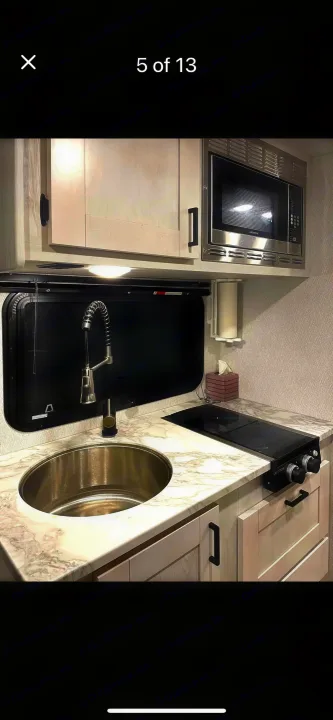 Stylish RV rental kitchen with stainless steel sink, Greystone microwave & cooktop, and marble-look counters.. east to west entrada 2023
