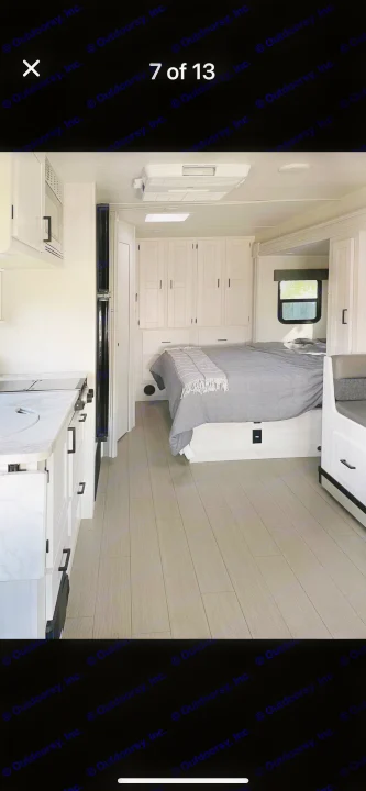Spacious RV rental interior featuring a modern kitchen, comfortable bedroom with built-in storage, and light wood-look flooring.. east to west entrada 2023