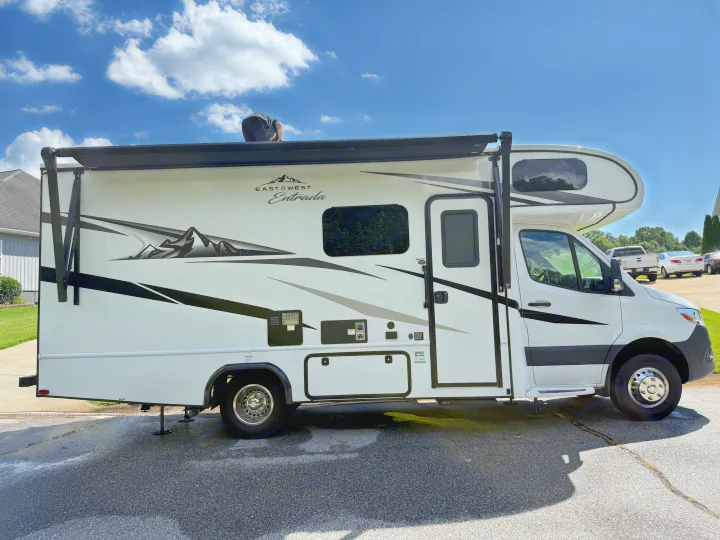 Person on roof cleaning a white East West Entrada motorhome. This RV is prepared for rental or routine maintenance.. east to west entrada 2023