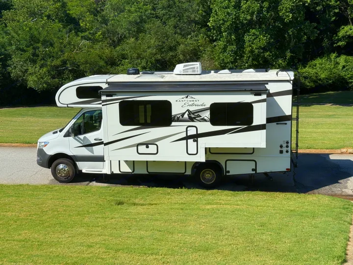 This EastWest Entrada motorhome, perfect for an **rv rental** adventure, is parked on asphalt with green grass and trees in the background.. east to west entrada 2023
