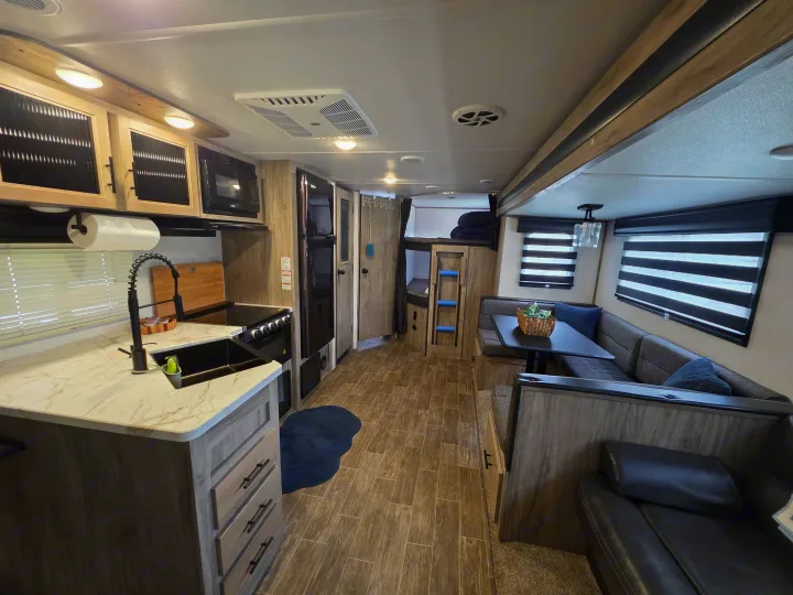 Inside this modern RV rental: kitchen, dinette, bunk beds, and a comfy sofa for travel comfort.. Forest River Cherokee Alpha Wolf 2021